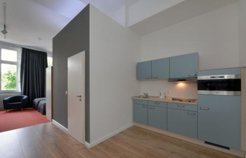 eine Küche mit blauen Schränken und einer offenen Tür in der Unterkunft Park Apartaments in Aachen