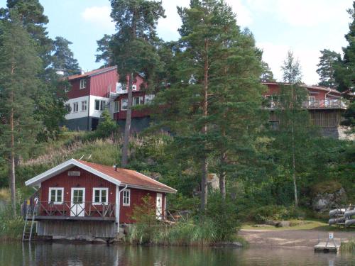 a red house on a hill next to a house on a lake at Stiftsgården Vårdnäs Hotell in Brokind