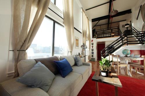 a living room with a couch and a large window at The Box House Hotel in Brooklyn