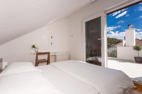 a white bedroom with a bed and a large window at Villa LeANN in Okrug Donji