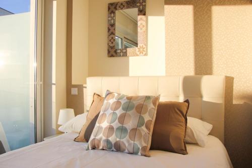 a bedroom with a white bed with pillows and a mirror at Terro Collection - Alcaide in Braga