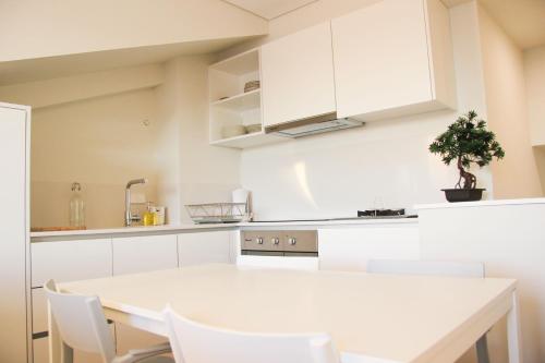 a white kitchen with a white table and white chairs at Terro Collection - Alcaide in Braga