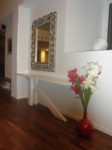 a table with a mirror and a vase with flowers at Hostal Doña Blanca in Sigüenza