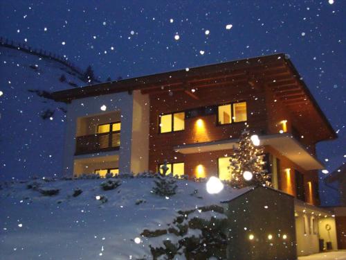 a building with a christmas tree in the snow at Appartements Montana in Vent
