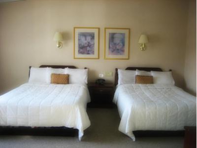 two beds in a hotel room with white sheets at Inn at Arbor Ridge Hotel and Conference Center in Hopewell Junction