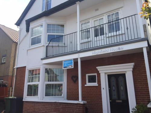 a white house with a balcony on top of it at Highfield Guest House in Sheringham
