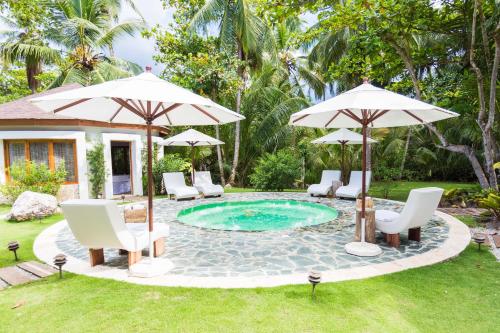 a pool with chairs and umbrellas in a yard at Apartment in Sublime Samana Résidence in Las Terrenas
