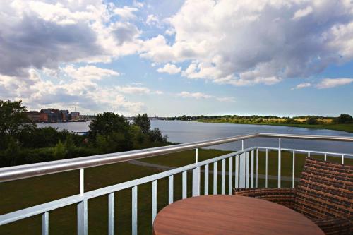 a table and chairs on a balcony with a view of a river at Hotel Warnow in Rostock