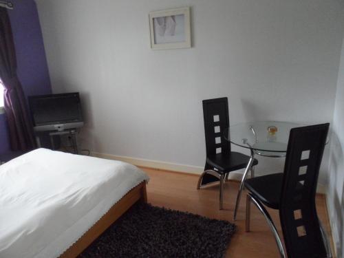 1 dormitorio con 1 cama, mesa y sillas en Homestay Oakridge Crescent, en Paisley