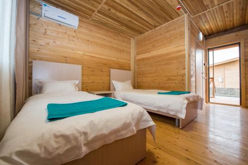 two beds in a room with wooden walls at Aquamarine Resort in Akshi