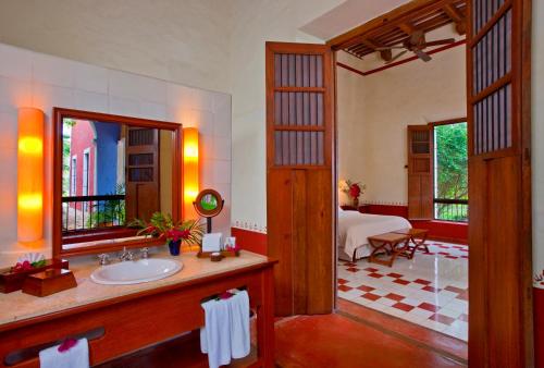 a bathroom with a sink and a mirror and a bedroom at Hacienda Santa Rosa de Lima in Santa Rosa