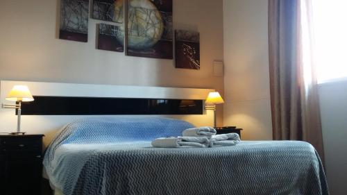 
a bed with a blanket on top of it next to a lamp at First Class Apartments in Córdoba
