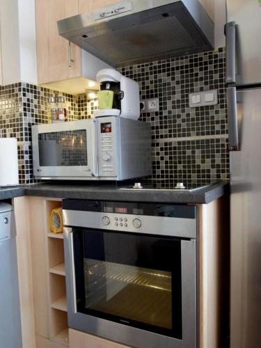 une cuisine avec une cuisinière et un micro-ondes dans l'établissement Auxmouettes GV2, à Saint-Hilaire-de-Riez