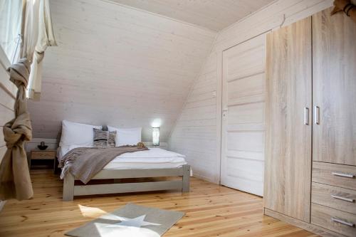 a bedroom with a bed with white walls and wooden floors at biale domki in Pobierowo