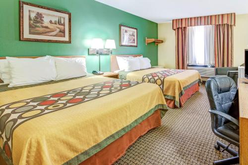 a hotel room with two beds and a chair at Super 8 by Wyndham McKinney/Plano Area in McKinney