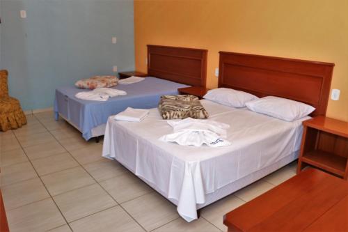 two beds in a hotel room with a purse on them at Pousada Recanto das Águas in Carmo do Rio Claro