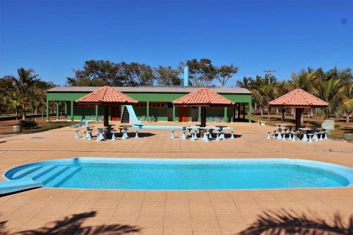 uma piscina com cadeiras e guarda-sóis e um resort em Pousada Recanto das Águas em Carmo do Rio Claro