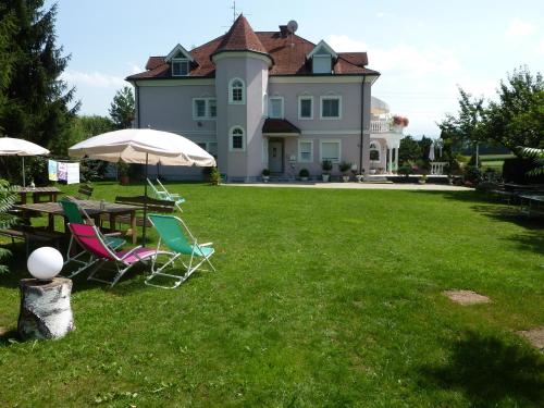 a house with a table and chairs and an umbrella at Villa Rose in Sankt Kanzian