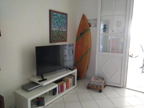 a living room with a flat screen tv and a surfboard at Savannah Guadeloupe in Saint-François