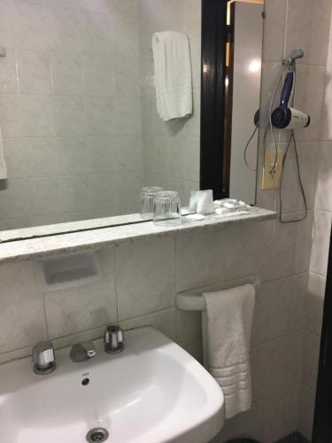 a white bathroom with a sink and a mirror at Hotel Centro Naval in Buenos Aires