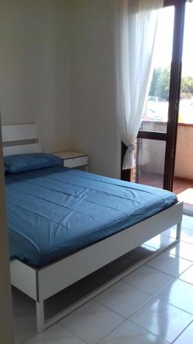 a bedroom with a bed with a blue comforter and a window at casa letizia in Porto Recanati