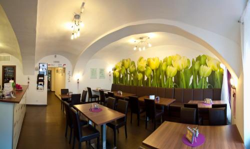 a restaurant with tables and yellow tulips on the wall at Hotel Berger in Kamenice nad Lipou