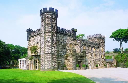 an old stone castle with a grass yard at Portmeirion Village & Castell Deudraeth in Porthmadog