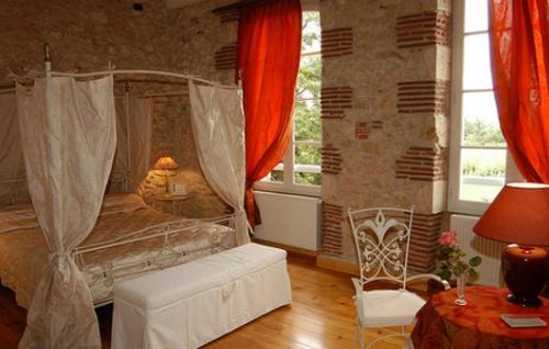 een slaapkamer met een bed, een tafel en een stoel bij Domaine de Paguy in Betbezer