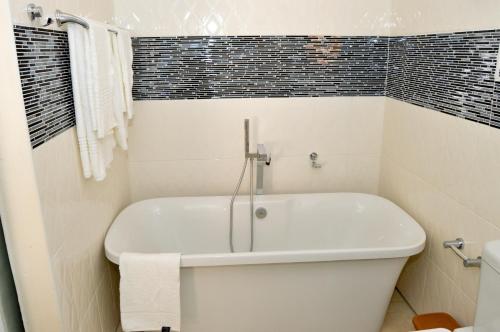 La salle de bains blanche est pourvue d'une baignoire blanche. dans l'établissement Golden Door Villa, à Gaborone