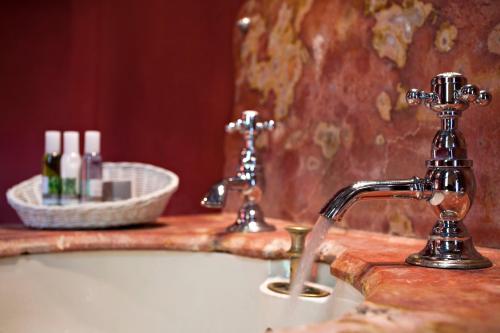 a bathroom sink with a faucet and a mirror at Le Castellas Hotel & SPA - TERITORIA in Collias