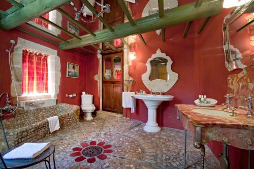 La salle de bains est pourvue de murs rouges, d'un lavabo et d'une baignoire. dans l'établissement Le Castellas Hotel & SPA - TERITORIA, à Collias