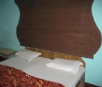 a bed with a wooden headboard and white pillows at Sai Palace in Agra