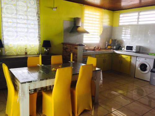 a kitchen with a dining table and yellow chairs at Le Papillon in Le Moule