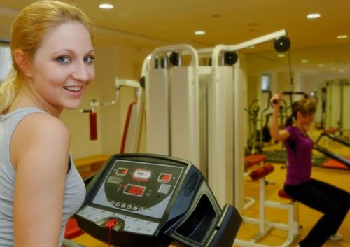 Una mujer corriendo en una cinta de correr en un gimnasio en Hotel Carat, en Erfurt