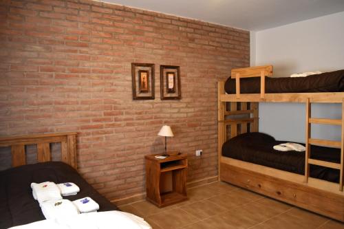 una camera con 2 letti a castello e un muro di mattoni di Hosteria Villa Santa Clara del Atuel a Valle Grande