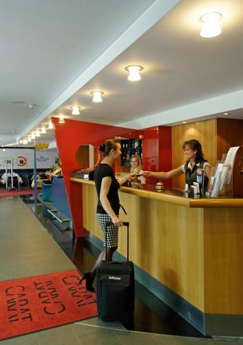 a man with a suitcase standing at a bar at Hotel Carat in Erfurt