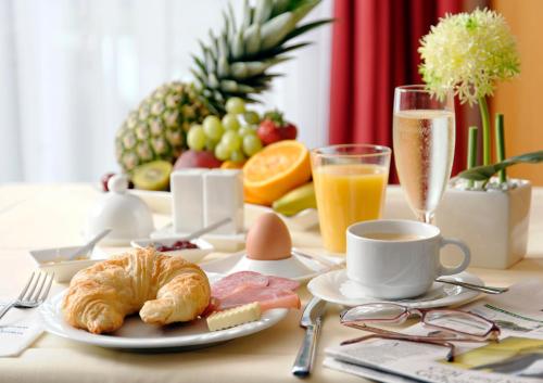 una mesa de desayuno con un cruasán y una taza de café en Hotel Carat en Erfurt