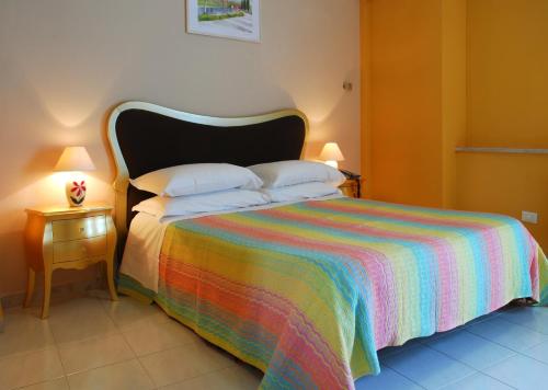 テーラモにあるHotel Michelangeloのベッドルーム1室(カラフルな毛布付きのベッド1台付)