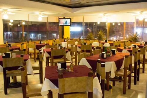 comedor con mesas y sillas y TV en Hotel Enriquez, en Coatzacoalcos