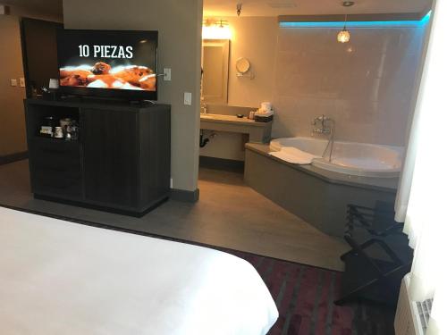 a bathroom with a tv and a tub and a sink at GreenTree Inn & Suites Los Angeles - Alhambra - Pasadena in Alhambra