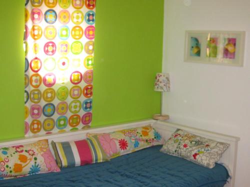 コンソラサオンにあるT2 House @ Consolação Penicheの緑の壁のベッドルーム1室、カラフルな枕付きのベッド1台が備わります。