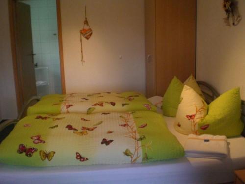 a bed with a green comforter with butterflies on it at Pension-Mummerliese in Goseck