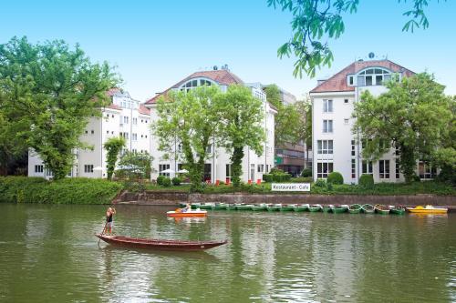 a man in a boat on a river with buildings at Domizil Tübingen in Tübingen