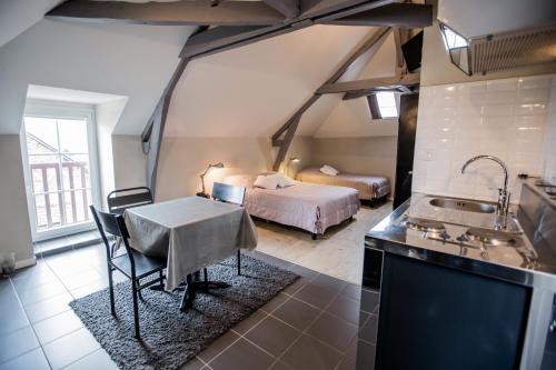 a kitchen with a table and a bed in a room at Les Appart'confort in Bain-de-Bretagne