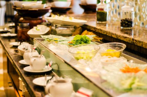 Una línea de buffet con platos y tazones de comida en Swiss-Belhotel Maleosan Manado, en Manado