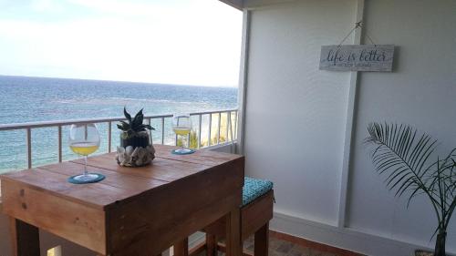 a table with two glasses of wine on a balcony at Beach front apartment in Luquillo in Luquillo