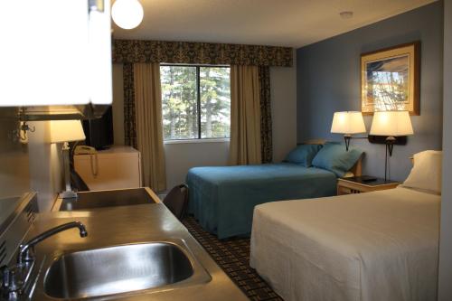 a hotel room with a sink and a bed at Hillcrest Motel in Swan Hills