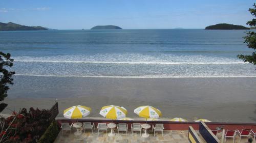 a group of chairs and umbrellas on the beach at Pousada Casa na Praia in Ubatuba