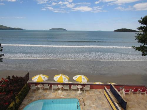 a view of the beach with a swimming pool and umbrellas at Pousada Casa na Praia in Ubatuba