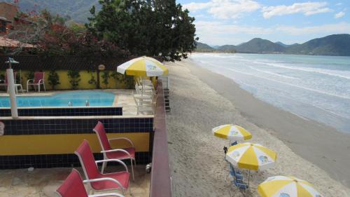 a view of a beach with chairs and umbrellas at Pousada Casa na Praia in Ubatuba